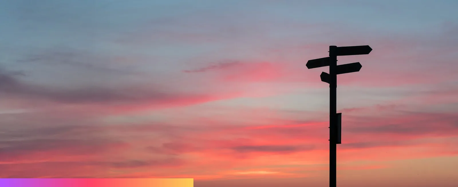 A signpost silhouetted against a sunset sky